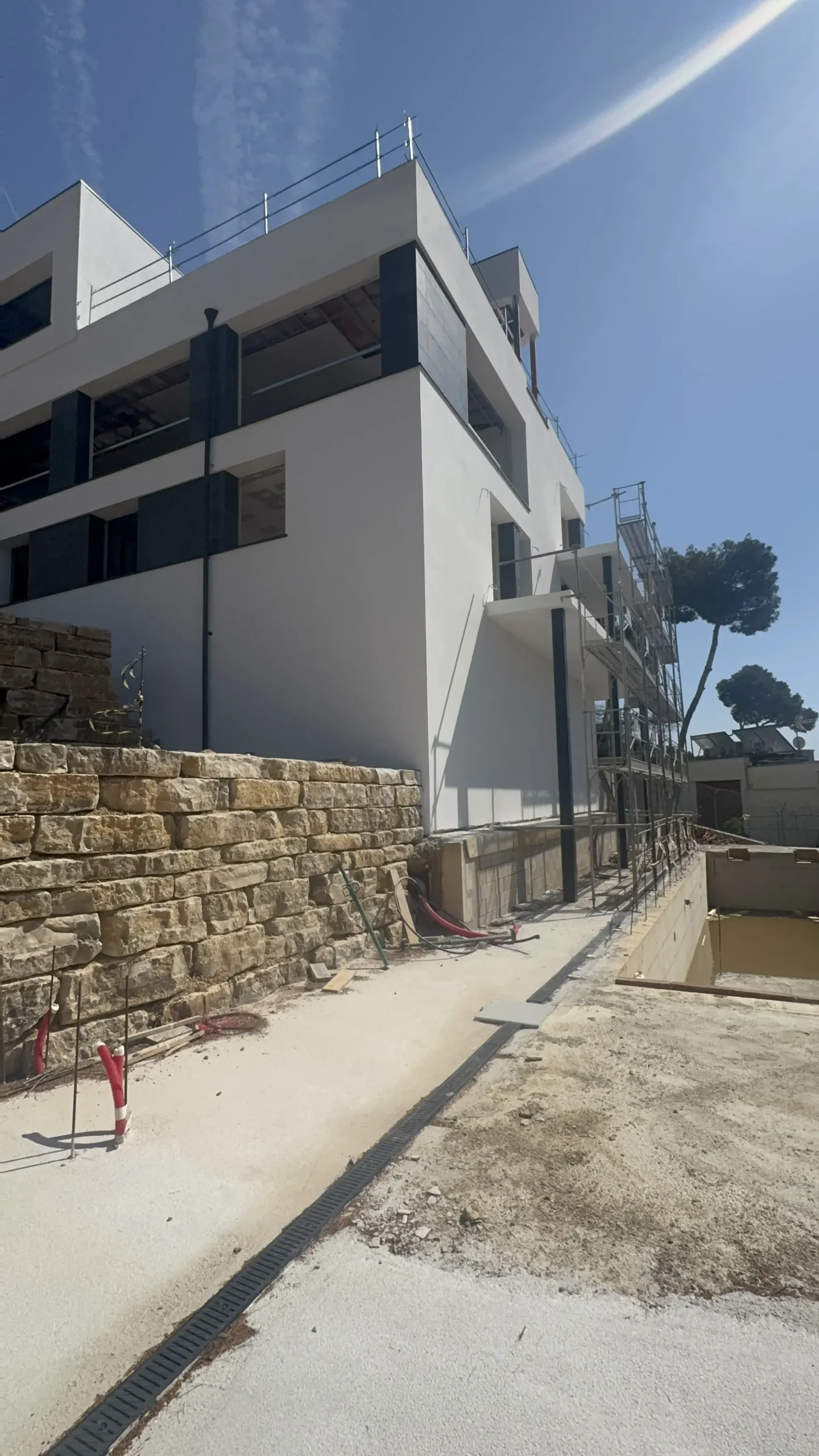 Fachada terminada de la villa con SATE, revestimiento porcelánico y muros de contención de piedra